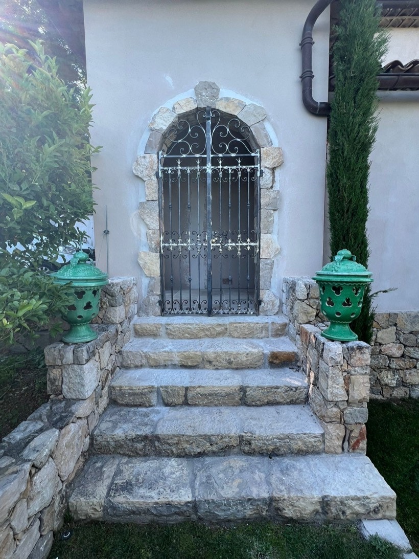 Grille de fenêtre cintrée en fer forgé sur perron, réalisée à Saint-Paul-de-Vence